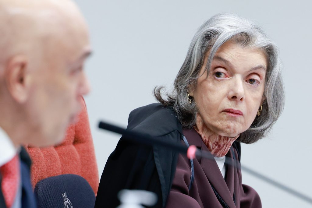 Ministra Cármen Lúcia, do STF, em sessão com expressão séria, ao lado de outras autoridades em ambiente institucional. STF visto