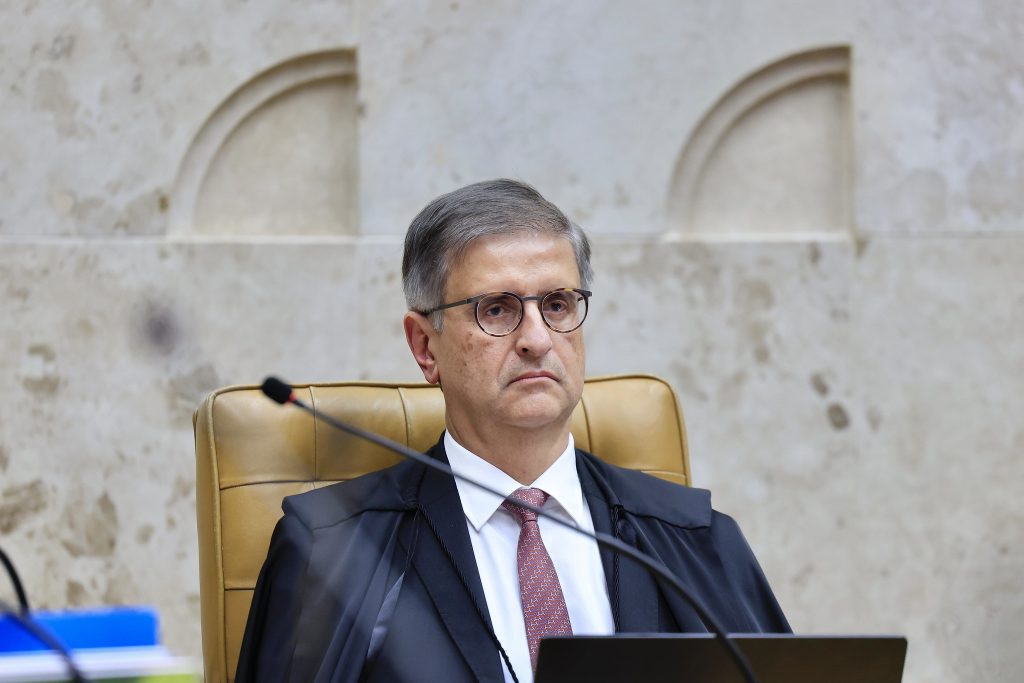 STF visto: PGR Paulo Gonet em sessão do STF, sentado em cadeira presidencial com toga e microfone à frente, em ambiente do plenário com assentos e estrutura de mármore ao fundo.
