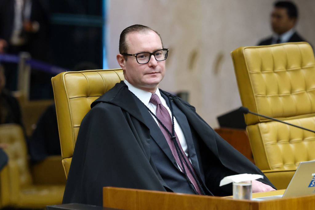 Ministro Cristiano Zanin (STF) sentado em sessão do Supremo Tribunal Federal, usando toga e óculos, com mesa e microfone ao fundo, STF visto