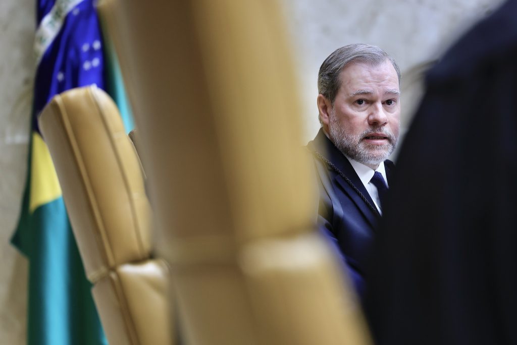 STF visto: Ministro Dias Toffoli (STF) em foto oficial, sentado em ambiente institucional com bandeira ao fundo, usando terno e gravata.