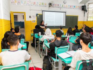 Professora em sala de aula com alunos, simbolizando a valorização do magistério e o novo piso salarial da educação básica aprovado pelo Senado.