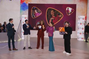 Encontro do Desafio Teleton com apresentação em palco e pessoas segurando materiais de divulgação, em evento que une esporte e solidariedade. Confira a data de início das doações.