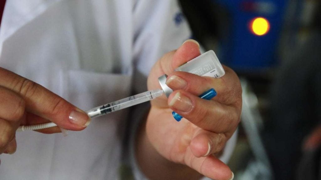 Vacinação contra gripe em Campinas: profissional de saúde aplica a vacina com seringa e frasco, com o paciente recebendo a dose nos centros de saúde da cidade. Crédito Arquivo/PMC.