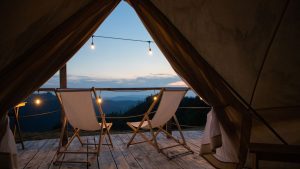 Glamping no Brasil com barraca de luxo iluminada sob céu estrelado em meio às montanhas.