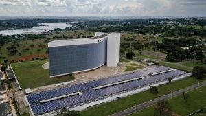 Pessoa segurando título eleitoral brasileiro em frente ao computador para regularizar situação para eleições 2026.