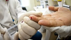 Profissional de saúde realizando teste rápido para dengue em unidade do SUS para diagnóstico precoce.