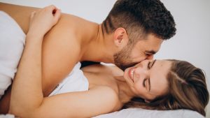 Casal abraçado e deitado em uma cama após o sexo, com expressão de carinho e intimidade; imagem para falar sobre pós-sexo e atitudes que aproximam