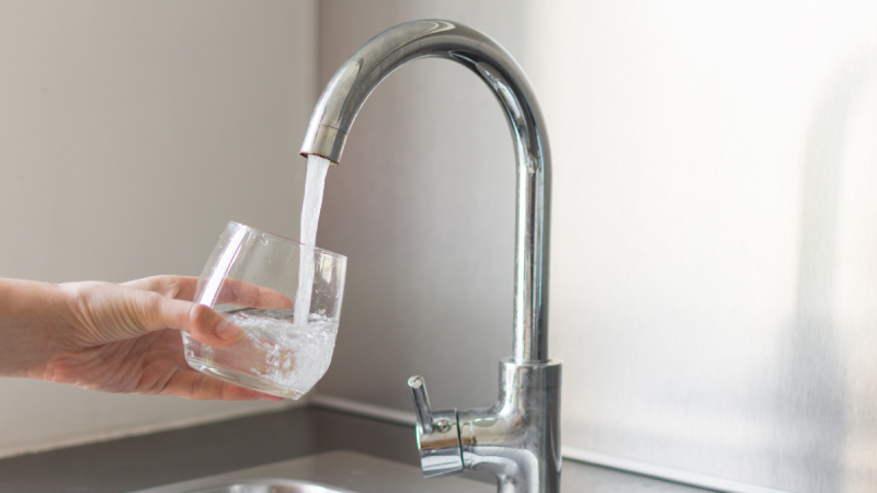 Torneira residencial despejando água para consumo em Hortolândia sob reclamações de odor e sabor alterados.
