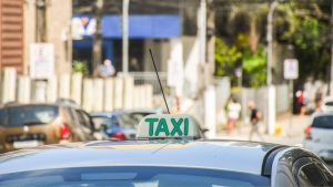 Táxi em São Vicente estacionado em ponto livre conforme nova legislação municipal de transporte.