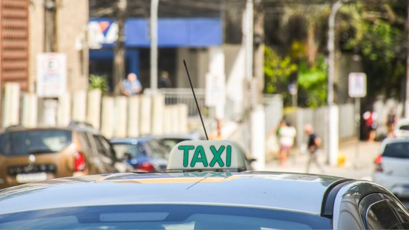 Táxi em São Vicente estacionado em ponto livre conforme nova legislação municipal de transporte.