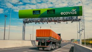 Pedágio eletrônico Free Flow na Rodovia Anchieta-Imigrantes com pórtico de cobrança e sinalização eletrônica, enquanto um caminhão passa pela pista de rodagem.
