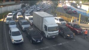 Operação de travessias por balsas no litoral paulista com veículos aguardando embarque em terminal hidroviário.