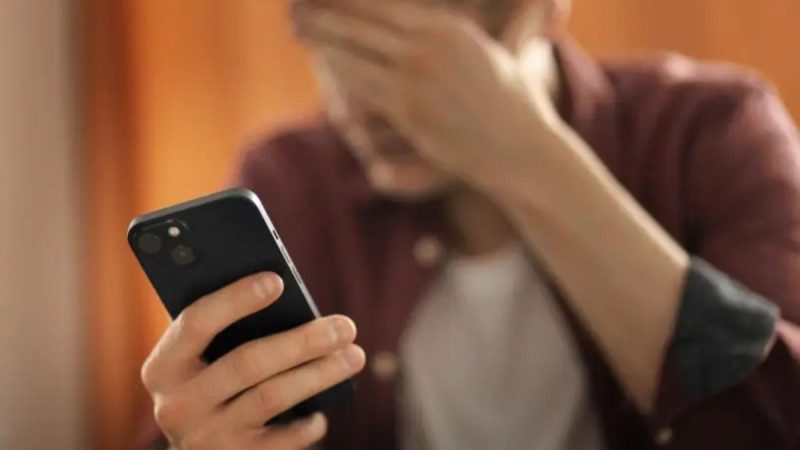 Empreendedor visualizando notificação de fraude financeira no celular, ilustrando golpes contra empreendedores.
