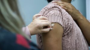 Profissional de saúde aplicando vacina em Vinhedo durante campanha de imunização na UBS Bela Vista.