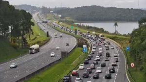 Manutenção no Sistema Anchieta-Imigrantes com sinalização de obras e fluxo de veículos em rodovia.