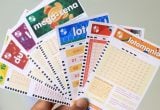 Mega-Sena acumula e prêmio sobe para R$ 135 milhões: imagem com bilhetes e cartões de loterias como Mega-Sena, Lotofácil e outros jogos de apostas na mão.