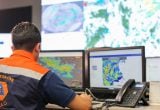 Defesa Civil alerta para pancadas isoladas e ventania no Estado de São Paulo, com agente em uniforme laranja e monitoramento em telas de meteorologia.