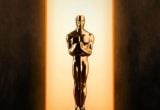 Oscar 2027: estatueta do prêmio em dourado sobre um fundo escuro, com iluminação quente ao fundo, simbolizando a disputa de filmes brasileiros na premiação