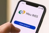 Pagamento do INSS: celular exibindo o app Meu INSS com botão Entrar com gov.br, mensagem sobre início do pagamento de julho, em contexto informativo.