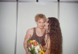 Juliano Floss e Marina Sena em foto romântica durante evento, com ele segurando um buquê colorido e ela de frente, em ambiente interno.