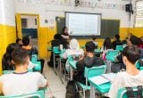 Professora em sala de aula com alunos, simbolizando a valorização do magistério e o novo piso salarial da educação básica aprovado pelo Senado.