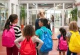 Alerta de tempestades provoca suspensão de aulas em três cidades da Baixada Santista, com crianças e estudantes usando mochilas em um corredor escolar.