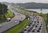 Manutenção no Sistema Anchieta-Imigrantes com sinalização de obras e fluxo de veículos em rodovia.