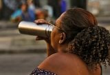 previsão do tempo em Campinas: Pessoa com cabelo cacheado segurando um guarda-chuva aberto em uma rua ao ar livre, em cena que sugere condições de tempo mais quentes e com temperaturas até 5°C acima da média na região de Campinas.